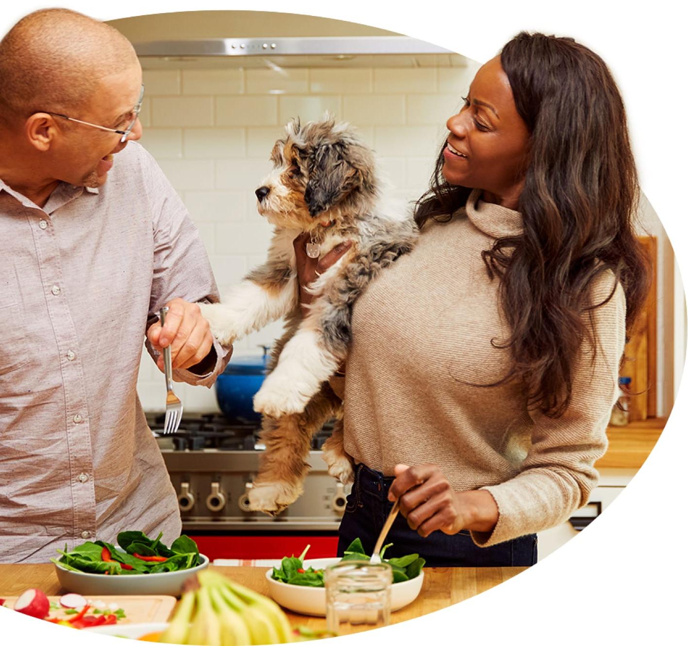 A woman holds an Aussie Doodle up as her mate asks the pup what’s for dinner.